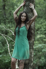 Portrait of a beautiful young dark-haired girl in a summer forest. There is artistic noise.