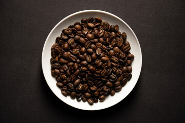 closeup of roasted coffee beans on white plate