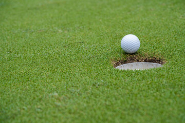 Golf ball is on a green lawn in a beautiful golf course with morning sunshine.
