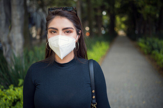 Young latin female in the park with face mask, new normal 2021. Portrait of latin young woman at the wood. New normal concept