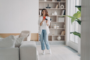 Attractive hispanic girl is shopaholic. Lady is holding card and going to buy through internet.