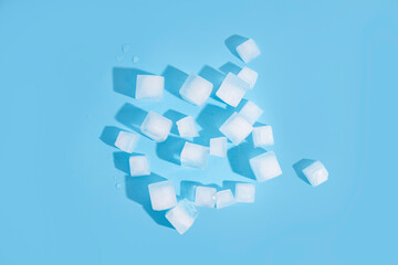 Many ice cubes on a blue background. Top view, flat lay