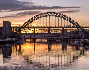The Tyne Bridge in Newcastle at sunset, reflecting in the almost still River Tyne beneath