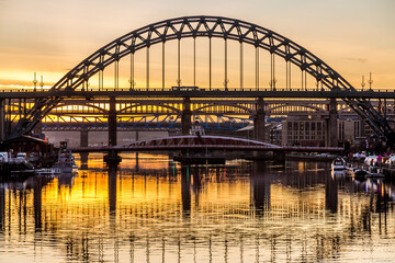 Fototapeta premium The Tyne Bridge in Newcastle at sunset, reflecting in the almost still River Tyne beneath