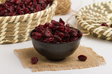 Dry cranberry served in bowl isolated on napkin side view of dry fruits on grey background