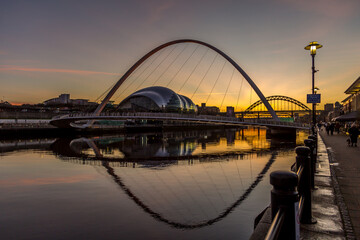 Fototapeta na wymiar The Millennium Bridge in Newcastle at sunset, reflecting in the almost still River Tyne beneath