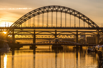 Fototapeta na wymiar The Tyne Bridge in Newcastle at sunset, reflecting in the almost still River Tyne beneath