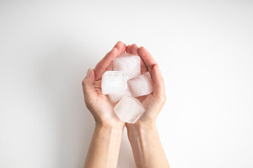 Ice cubes in female palms on a white background. Top view, flat lay