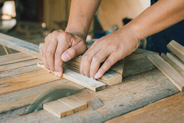 Asian carpenter is using a circular saw to cut wood to construct a storage box on a desk table at his factory. Working as your own boss at home concept