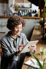 Smiling businesswoman, owner of cafe or restaurant, looking through online orders of clients while...