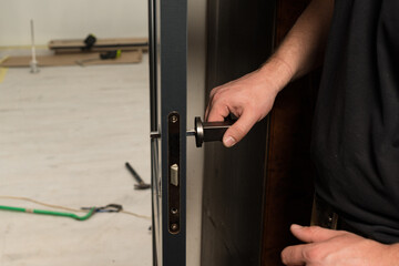 A carpenter installs a metal doorknob for an interior door,