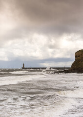 Fototapeta premium Looking across King Edwards Bay at the rough seas on a cloudy day at Tynemouth, England