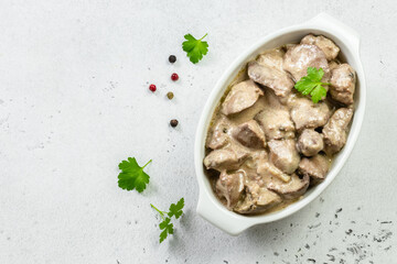 Sauteed chicken liver, cream sauce in ceramic dish. Top view, copy space, flat lay.