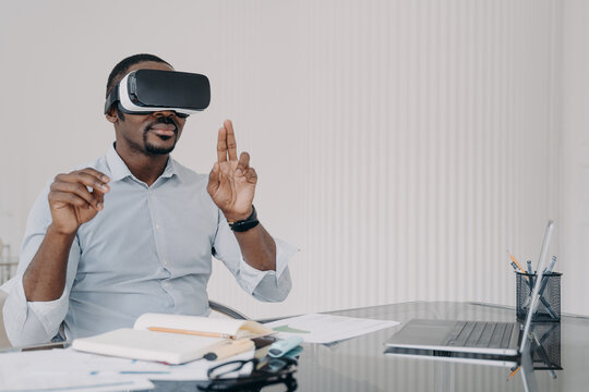 African american man IT engineer developer in VR glasses working with virtual reality at office desk - Powered by Adobe