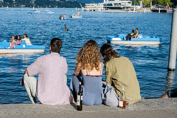 Jugendliche sitzen am Ufer des Vierwaldstättersees, in Luzern, Schweiz