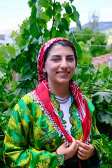 Turkish village woman dressed in traditional clothes with grape vineyard background. 