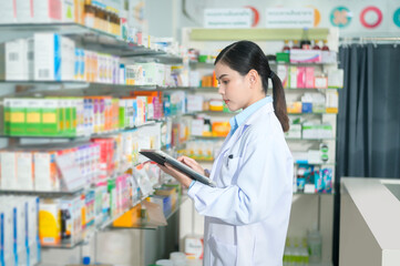 Portrait of female pharmacist using tablet in a modern pharmacy drugstore.