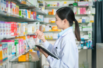 Portrait of female pharmacist using tablet in a modern pharmacy drugstore.