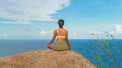 Beautiful asian woman in sportswear doing yoga on seaside mountain peak after trekking, Travel and meditation concept.