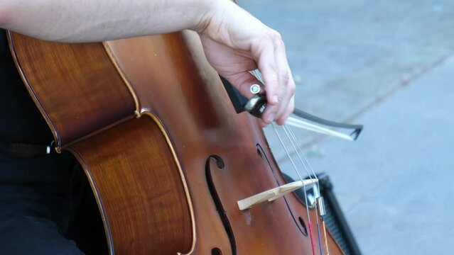 A young man is playing his cello at street as a close-up slow-motion view