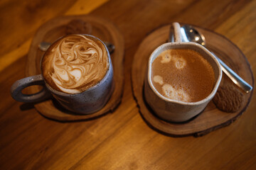 Two cups of cappuccino americano coffee on wooden table in cafe. Selective sharpness