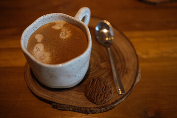 Cappuccino coffee in light cup on a wooden table in cafe. Selective sharpness