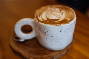 Cappuccino coffee in light cup on a wooden table in cafe. Selective sharpness