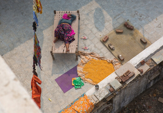 An Indian woman relaxes under the sun on the roof of her house in Pushkar. Sleeping woman. Heat wave in India