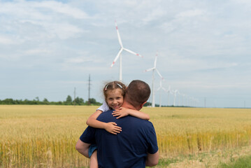 A girl and her dad look at the wind generator in the field. Ecology. Future.