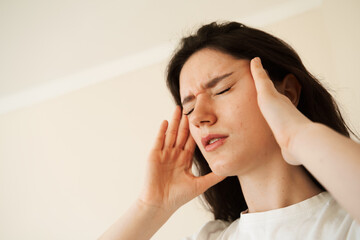 Depressed girl with migraine headache. Sad woman touches temples because of stress and despair in...