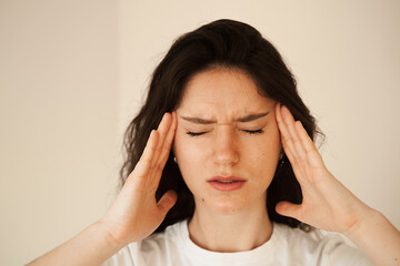 Depressed girl with migraine headache. Sad woman touches temples because of stress and despair in her life. Problems in life.