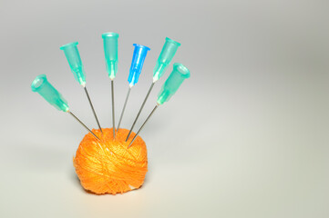 Needles Stuck into an orange skein of thread. Space for text. Pharmaceutical images with copy space.