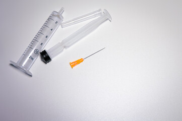 Parts of a medical syringe with a bright orange needle. Space for text. Pharmaceutical images with...