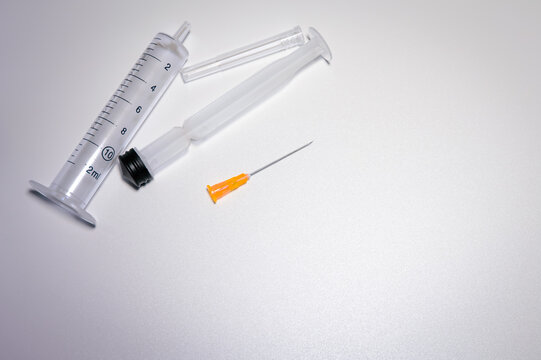 Parts of a medical syringe with a bright orange needle. Space for text. Pharmaceutical images with copy space. 