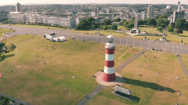 Aerial drone shot of a red and white striped lighthouse on the coast in Plymouth, UK