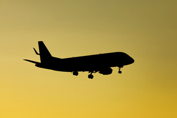 Naklejka na ściany i meble Airplane silhouette in sunset orange sky.