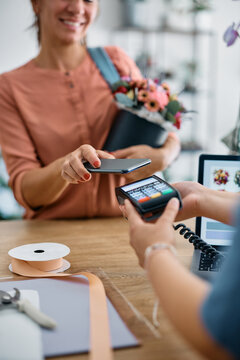 Close up of flower shop customer playing contactless with her smart phone.