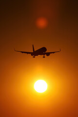 Airplane silhouette against the background of the sun disk.
