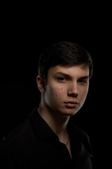 Obraz premium Portrait of a brunette teenager, in a black shirt on a navy blue background.