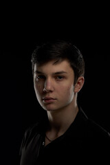 Fototapeta premium Portrait of a brunette teenager, in a black shirt on a navy blue background.