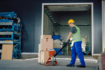 Male worker pushing packages on pallet jack while working warehouse.