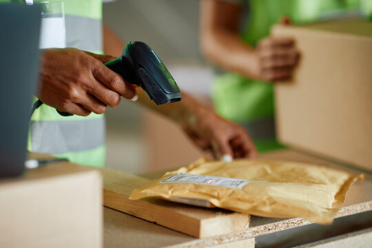 Close up of warehouse worker scanning labels on packages.