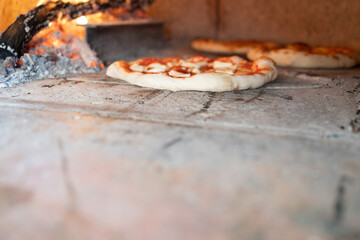 traditional neapolitan pizza coking in the wood fired oven with copy space, in the background...