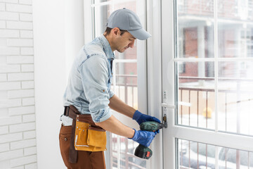 handsome young man installing bay window in a new house construction site.