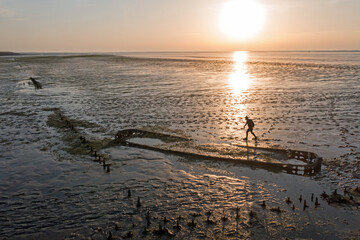 Fototapeta na wymiar Aerial from walking on the mud from the Wadden Sea with an old ship wreck in Friesland the Netherlands at sunset
