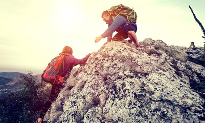 People helping each other hike up a mountain, Giving helping hand and teamwork concept - obrazy, fototapety, plakaty