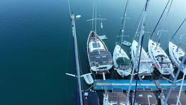 Aerial top-down view of docked sailboats. Top down view of yachts in the marina. Sailboats and regular Boats moured in Palairos Marina Greece. Sailboats and catamarans anchored in the harbour.