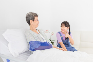 Fototapeta premium Asian patient sick and admit in hospital ,children visit patient and show show thumb up sign with hand, they feeling happy and smile, elderly healthcare