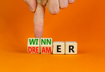 Winner or dreamer symbol. Concept words Winner or dreamer on wooden cubes. Businessman hand. Beautiful orange table orange background. Business and Winner or dreamer concept. Copy space.