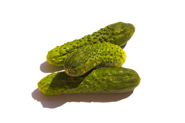 three green cucumbers lie on a white background